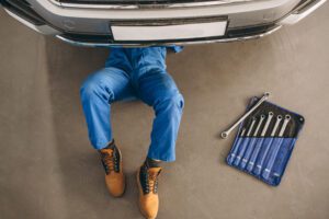 A photo of a person working beneath a car with a toolbox near them. 